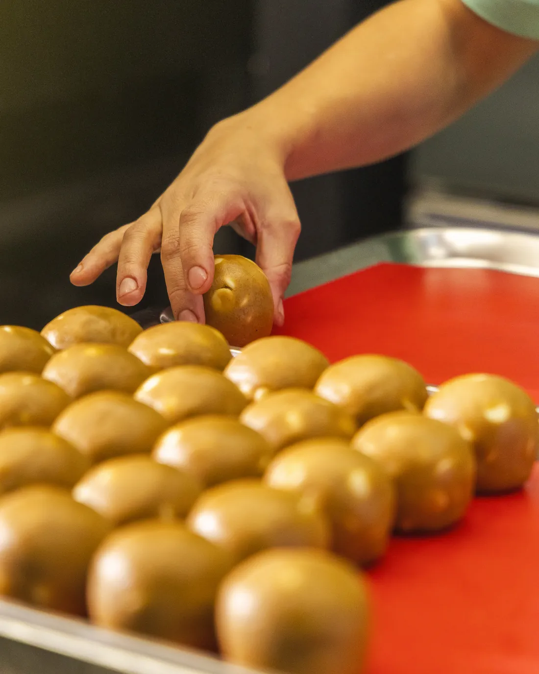 Bolinhas de massa sendo dispostas na bandeja, na cozinha da Brookies
